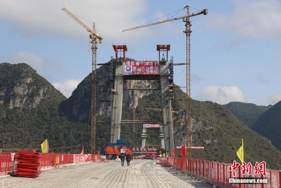 11月22日，正在建設(shè)中的峰林特大橋。當(dāng)日，隨著1470噸裝配化預(yù)制中橫梁提升到位，貴州省黔西南布依族苗族自治州興義環(huán)城高速公路峰林特大橋4號主塔中橫梁成功吊裝，由此刷新了山區(qū)峽谷橋梁預(yù)制吊裝混凝土構(gòu)件重量世界記錄。峰林特大橋是屬全線控制性工程。大橋跨越馬嶺河峽谷，全長1163米，主跨采用550米懸索橋，橋面離谷底364.2米，是中國山區(qū)第一座大跨徑鋼混疊合梁懸索橋。中新社記者 瞿宏倫 攝