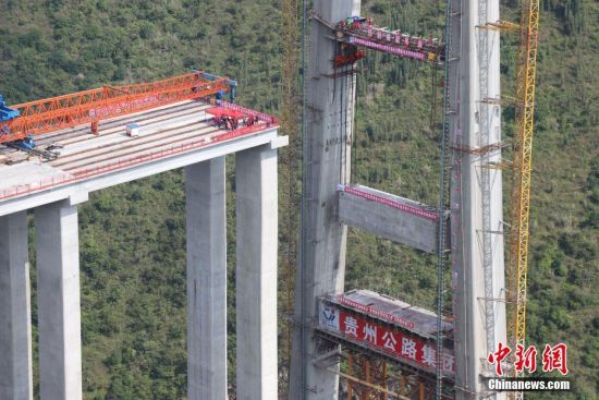 11月22日，峰林特大橋4號主塔中橫梁正在吊裝。當(dāng)日，隨著1470噸裝配化預(yù)制中橫梁提升到位，貴州省黔西南布依族苗族自治州興義環(huán)城高速公路峰林特大橋4號主塔中橫梁成功吊裝，由此刷新了山區(qū)峽谷橋梁預(yù)制吊裝混凝土構(gòu)件重量世界記錄。峰林特大橋是屬全線控制性工程。大橋跨越馬嶺河峽谷，全長1163米，主跨采用550米懸索橋，橋面離谷底364.2米，是中國山區(qū)第一座大跨徑鋼混疊合梁懸索橋。中新社記者 瞿宏倫 攝