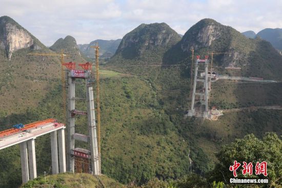 11月22日，正在建設(shè)中的峰林特大橋。當(dāng)日，隨著1470噸裝配化預(yù)制中橫梁提升到位，貴州省黔西南布依族苗族自治州興義環(huán)城高速公路峰林特大橋4號主塔中橫梁成功吊裝，由此刷新了山區(qū)峽谷橋梁預(yù)制吊裝混凝土構(gòu)件重量世界記錄。峰林特大橋是屬全線控制性工程。大橋跨越馬嶺河峽谷，全長1163米，主跨采用550米懸索橋，橋面離谷底364.2米，是中國山區(qū)第一座大跨徑鋼混疊合梁懸索橋。中新社記者 瞿宏倫 攝