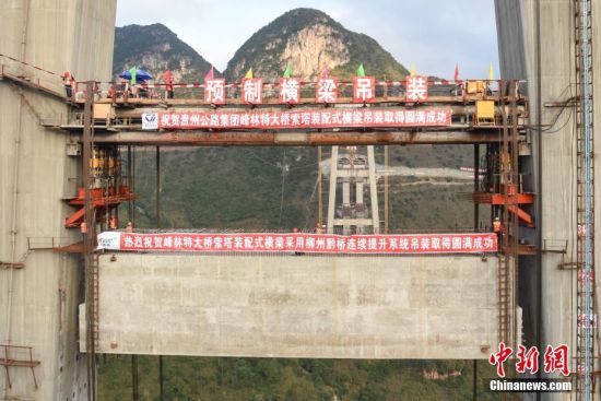 11月22日，隨著1470噸裝配化預(yù)制中橫梁提升到位，貴州省黔西南布依族苗族自治州興義環(huán)城高速公路峰林特大橋4號主塔中橫梁成功吊裝，由此刷新了山區(qū)峽谷橋梁預(yù)制吊裝混凝土構(gòu)件重量世界記錄。峰林特大橋是屬全線控制性工程。大橋跨越馬嶺河峽谷，全長1163米，主跨采用550米懸索橋，橋面離谷底364.2米，是中國山區(qū)第一座大跨徑鋼混疊合梁懸索橋。中新社記者 瞿宏倫 攝